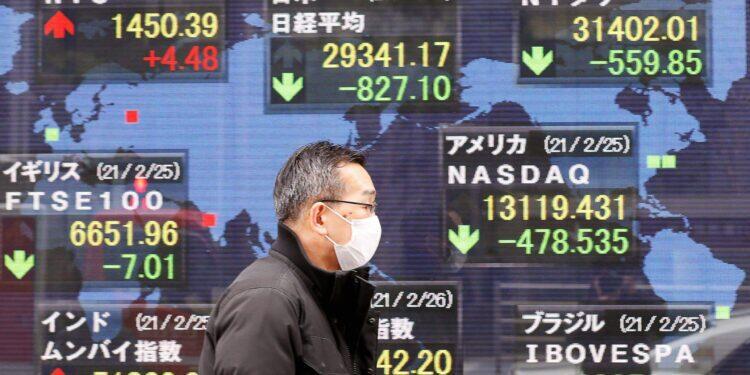 FILE PHOTO: A man walks past a stock quotation board at a brokerage in Tokyo, Japan February 26, 2021. REUTERS/Kim Kyung-Hoon/File Photo